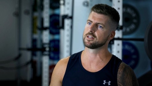 Darren Williams yn eistedd yn ei gadair olwyn yn cael ei gyfweld yn y gampfa 